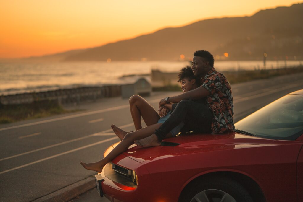 Couple enjoying the sunset on top of their car in Los Angeles