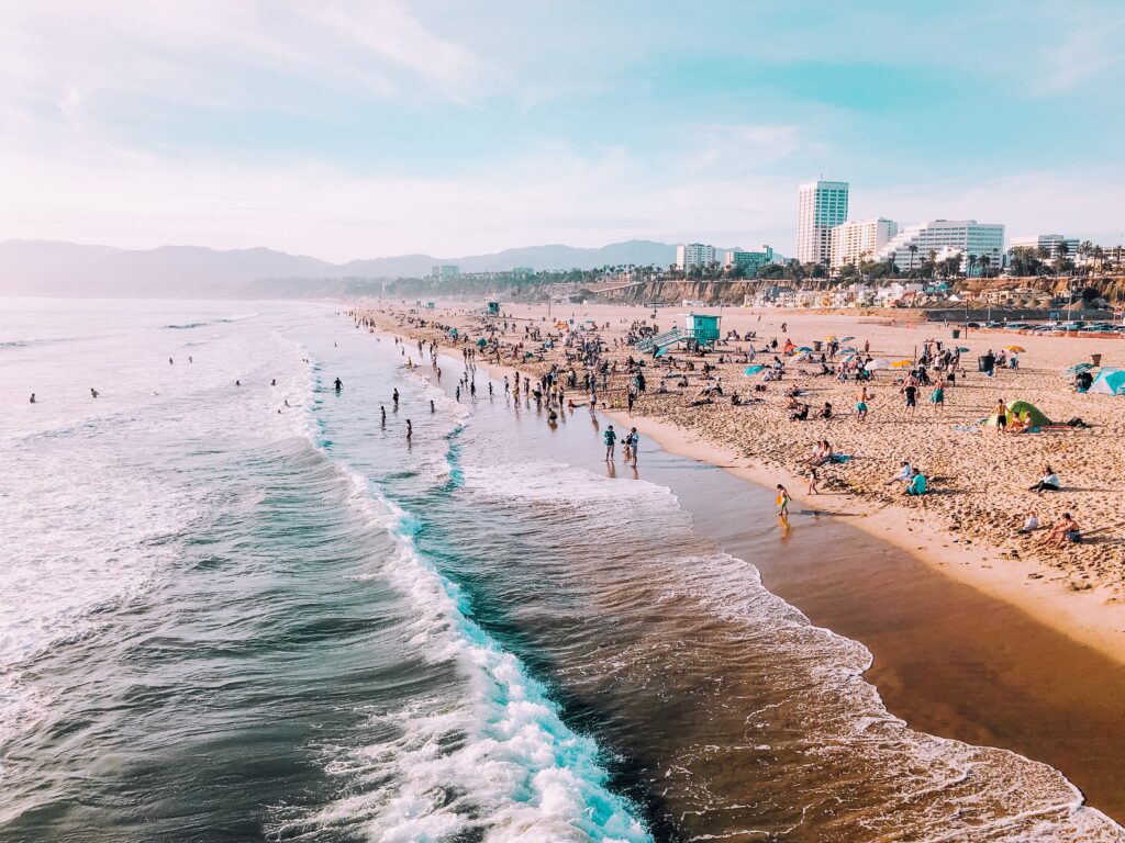 Photo by Gerson on Unsplash. Santa Monica Beach with many people at shoreline