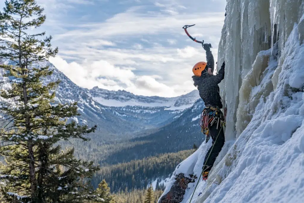 Woman ice climbing in Bozeman Montana with the mountains in the view